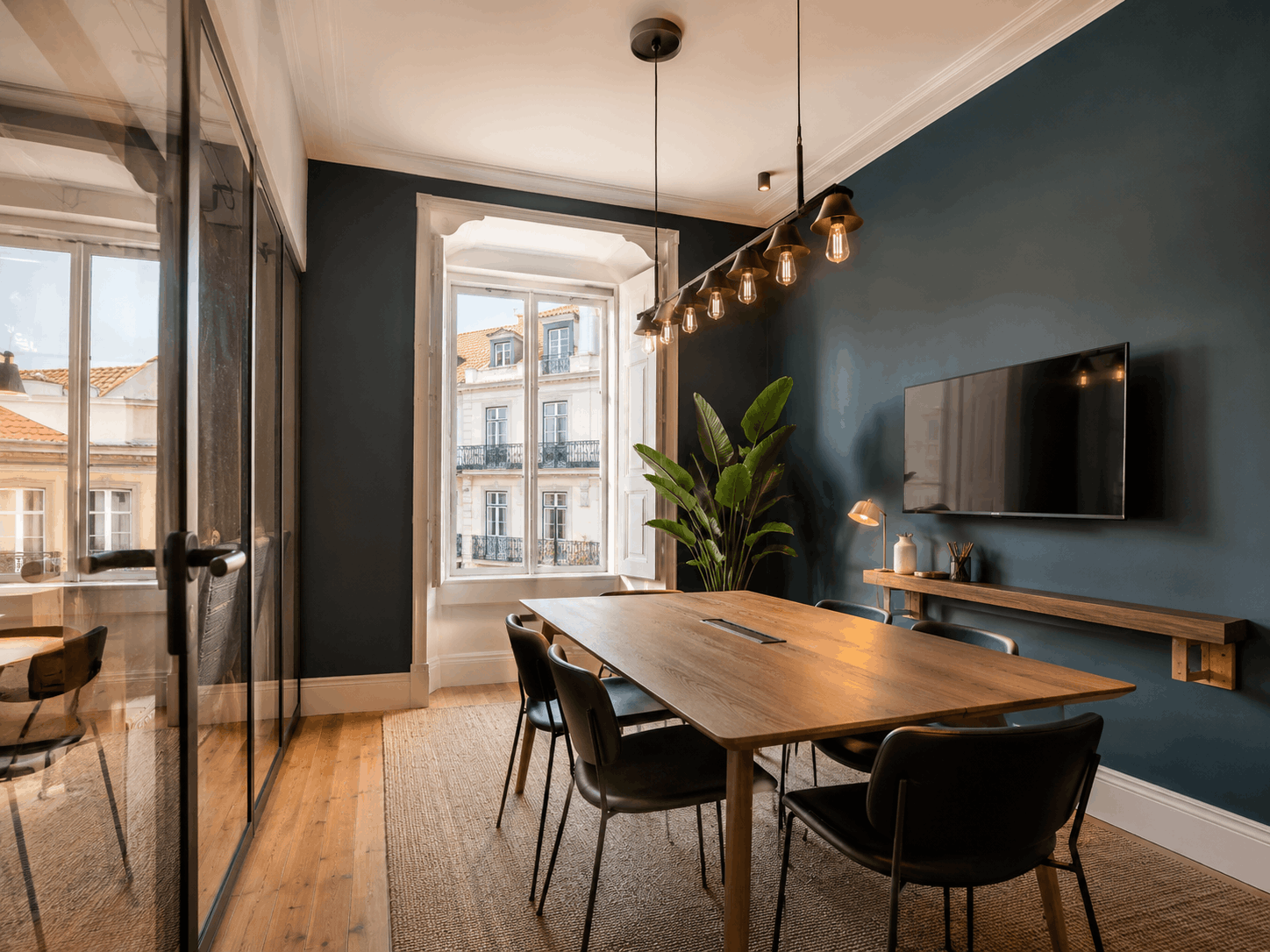 Sala de reunião criativa com mesa de madeira e parede azul-esverdeada